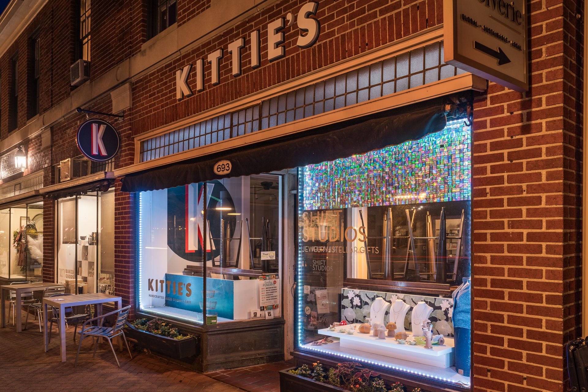 Exterior of Kittie’s coffee shop in downtown Worthington, Ohio, at night, with brick storefront, outdoor seating, and illuminated display windows.